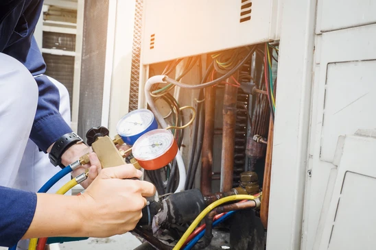 Technicien en tenue de travail bleue effectuant maintenance sur syst&egrave;me de climatisation r&eacute;sidentiel