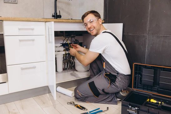 plombier Professionnel travaillant sur les conduites d'eau et les filtrers sous l'&eacute;vier dans la cuisine, effectuant l'entretien et l'installation